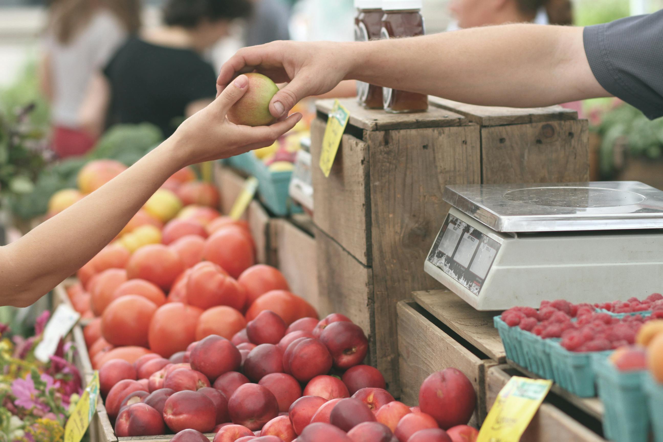 Customer picking up a box of vegetables from a farm stand.